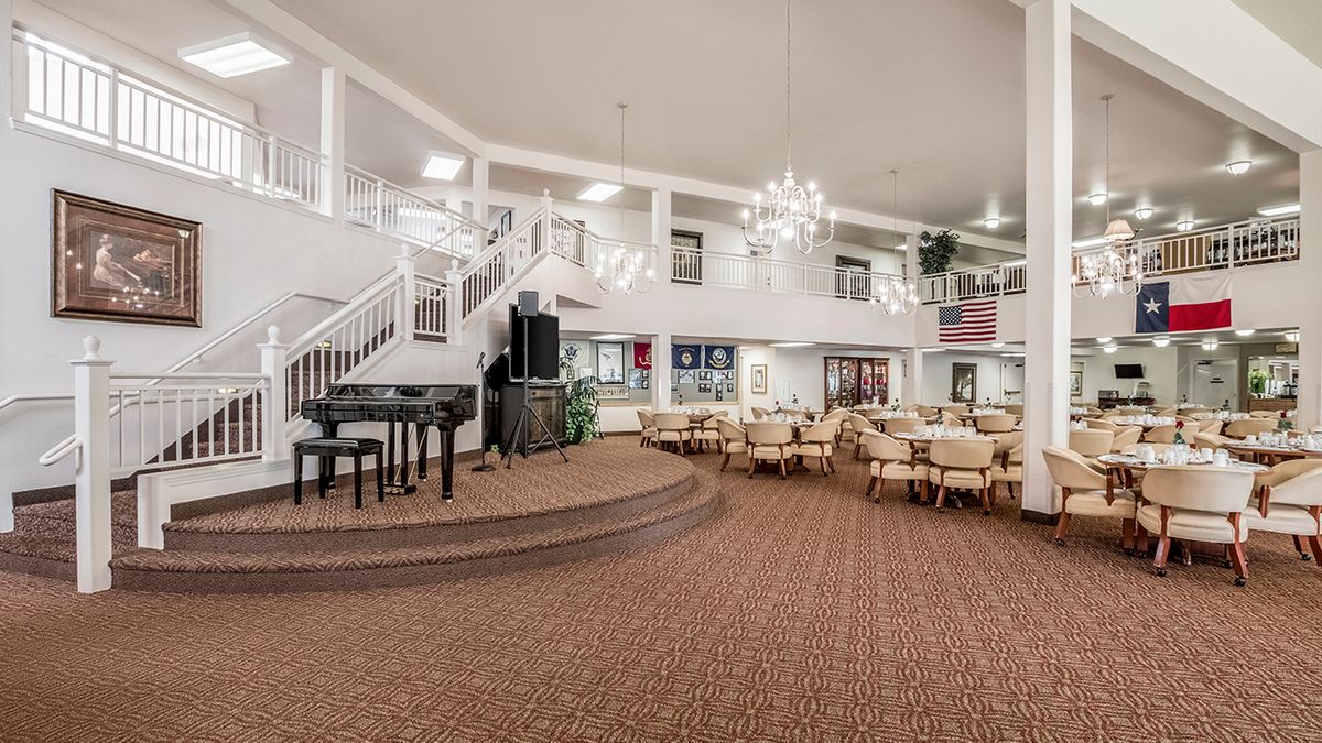 Spacious dining area with a stage and elegant chandeliers.