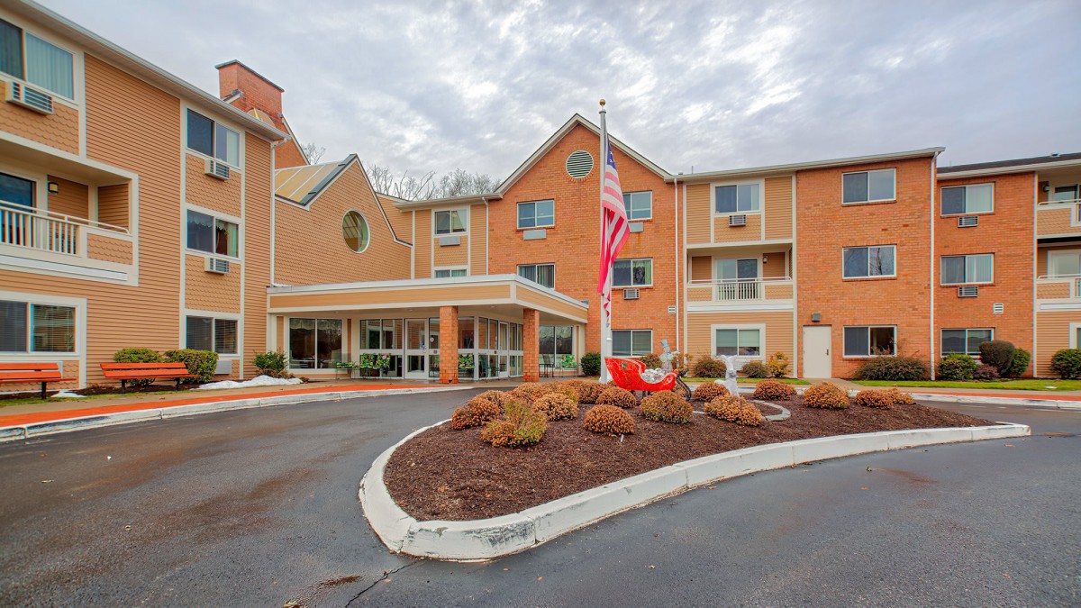 The exterior view of a hotel building with neatly landscaped grounds and an American flag flying out front.