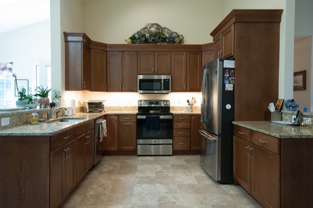 A modern kitchen featuring wooden cabinets, stainless steel appliances including a microwave, oven, and fridge.