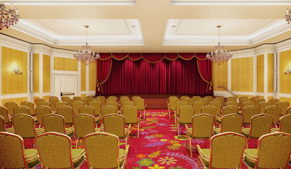 Empty auditorium with arranged seating and a stage with red curtains.