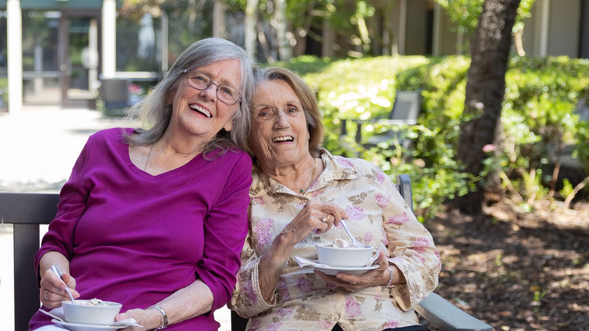 Two elderly women enjoying time together in a garden.