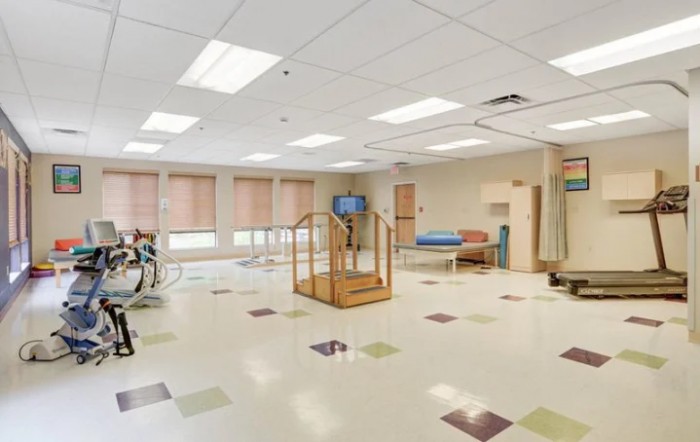 A spacious rehabilitation therapy room equipped with exercise equipment and a wooden staircase.