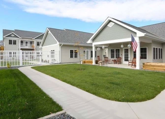 A residential building with a well-maintained lawn and an American flag on the porch.