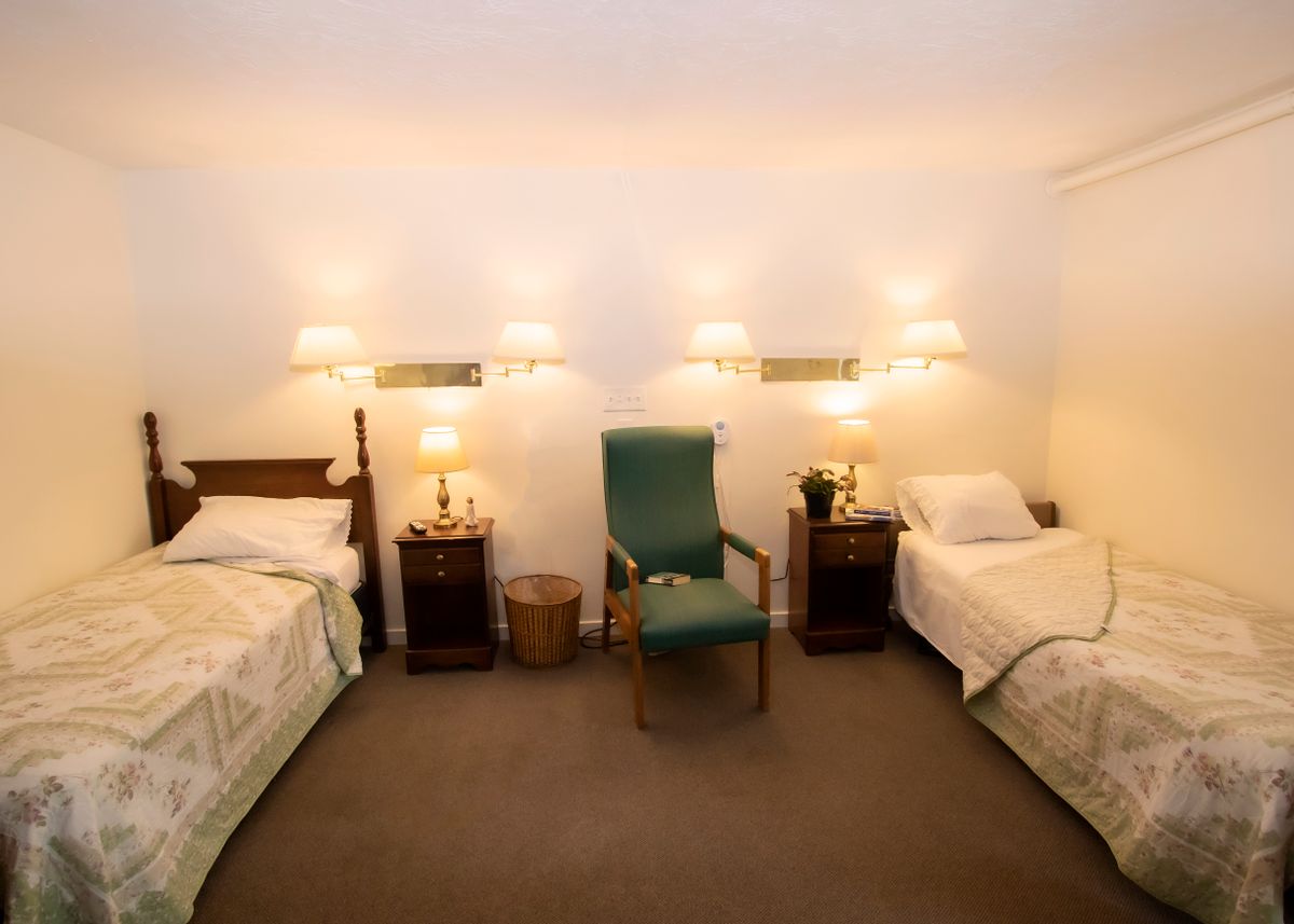 A cozy bedroom featuring twin beds with warm lighting and classic furnishings.