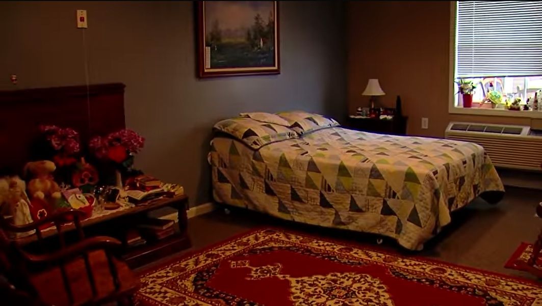 A cozy bedroom with a quilted bed, side table, and a decorative rug.