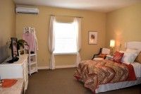 A cozy bedroom with a bedspread, window with curtains, and warm lighting.