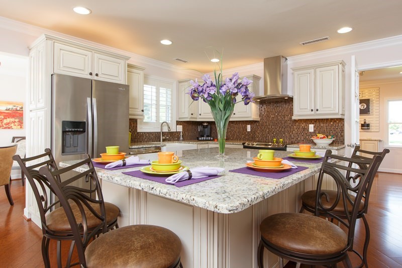 A modern kitchen with a central island featuring colorful table settings and flowers.