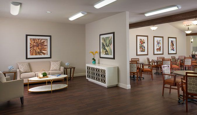 A modern, well-lit living room with elegant furniture and framed artwork on the walls.