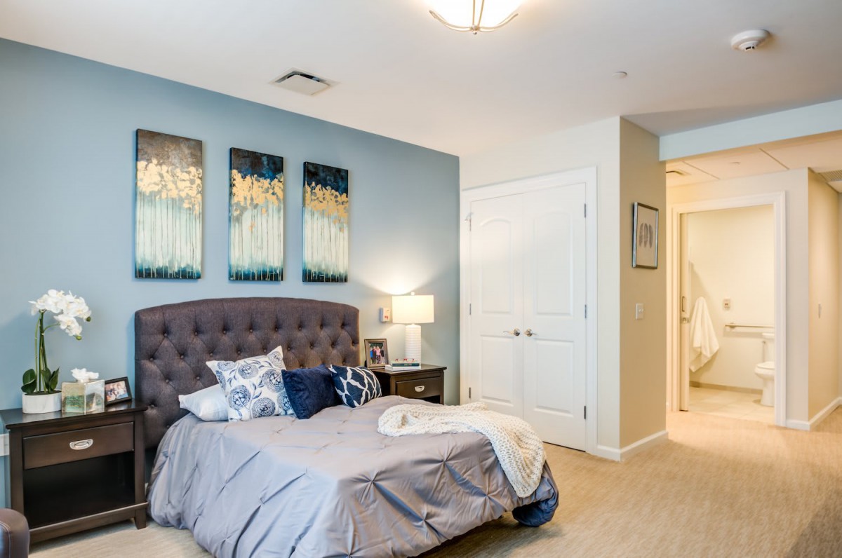 A cozy bedroom featuring a tufted headboard, abstract artwork, and soft lighting.