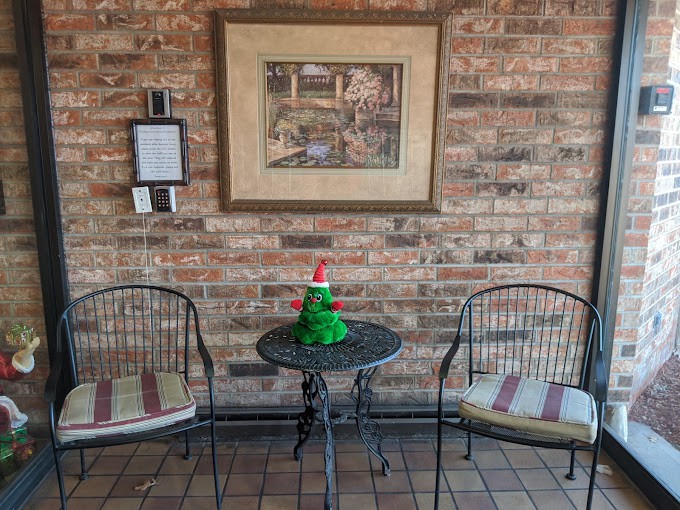 A cozy corner with two chairs, a small table adorned with festive decor, and a framed painting on a brick wall.