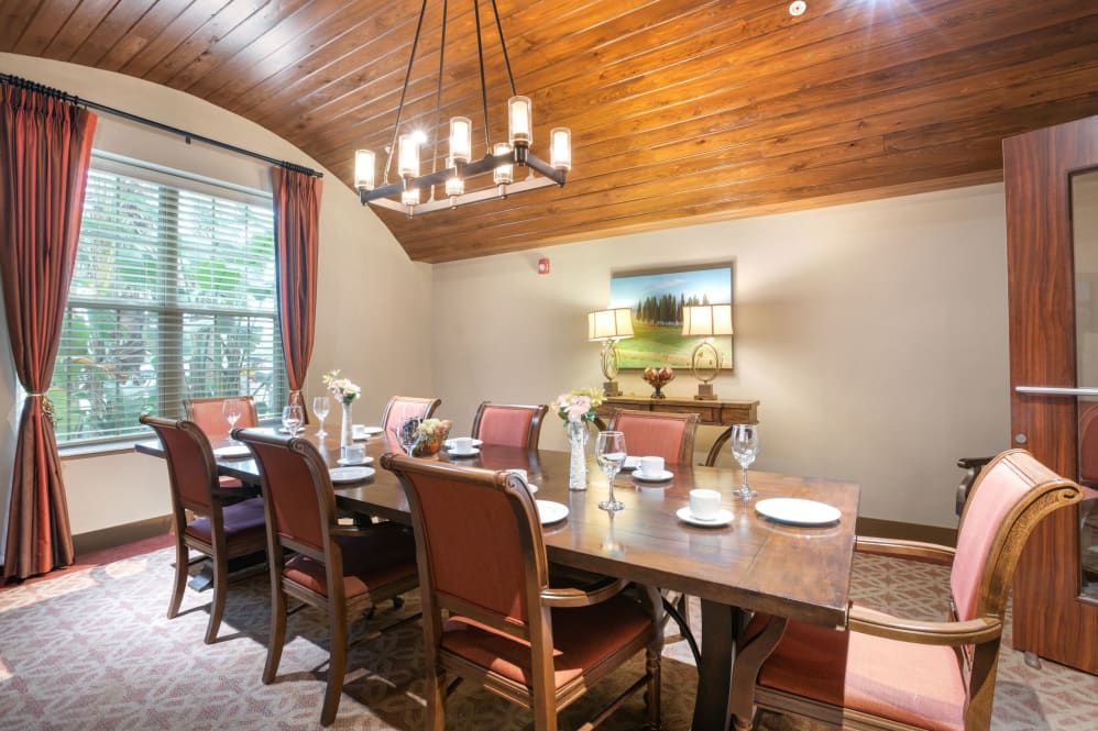 A cozy dining room with a large table, surrounded by cushioned chairs and topped with elegant tableware.