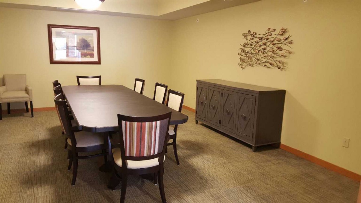 A dining room setup with a large table, chairs, artwork on the wall, and a sideboard.