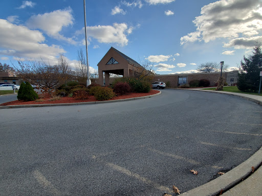 A view of a commercial building with a landscaped parking area under a partly cloudy sky.
