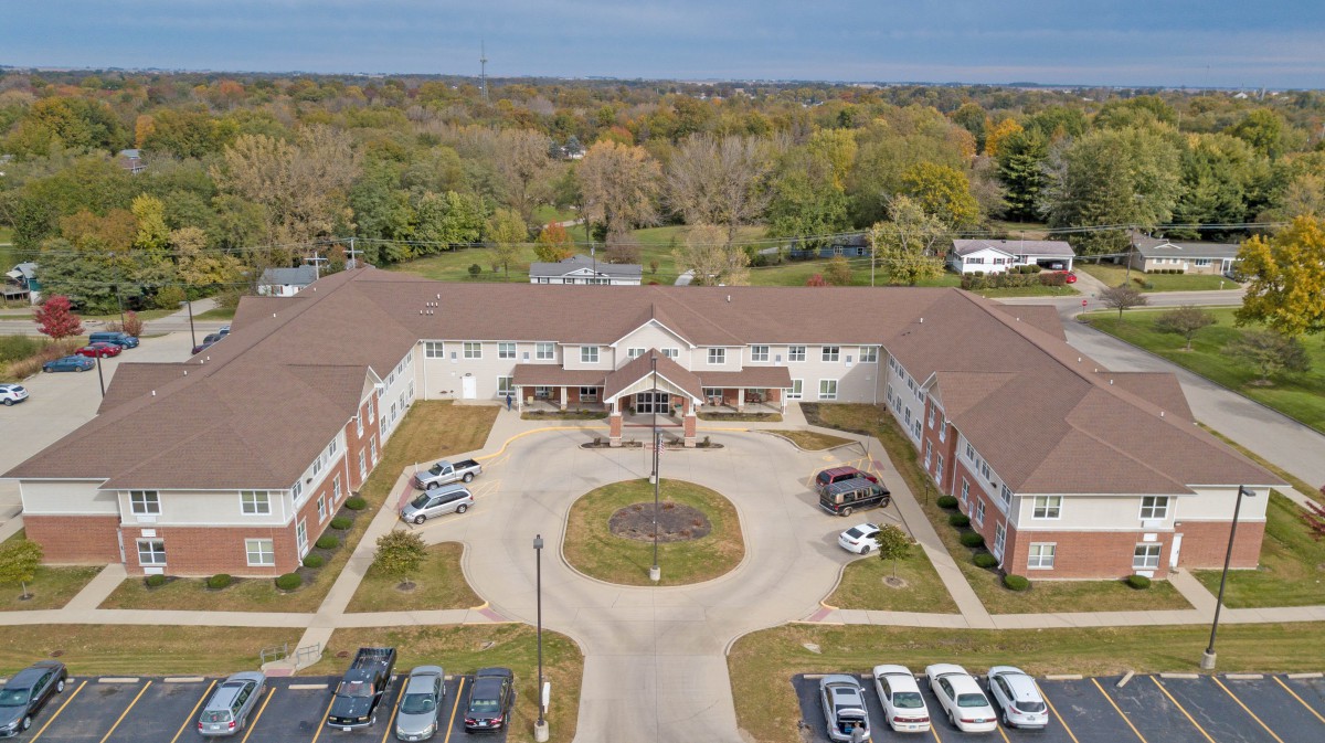 Aerial view of a large building with a circular driveway and surrounding parking area.