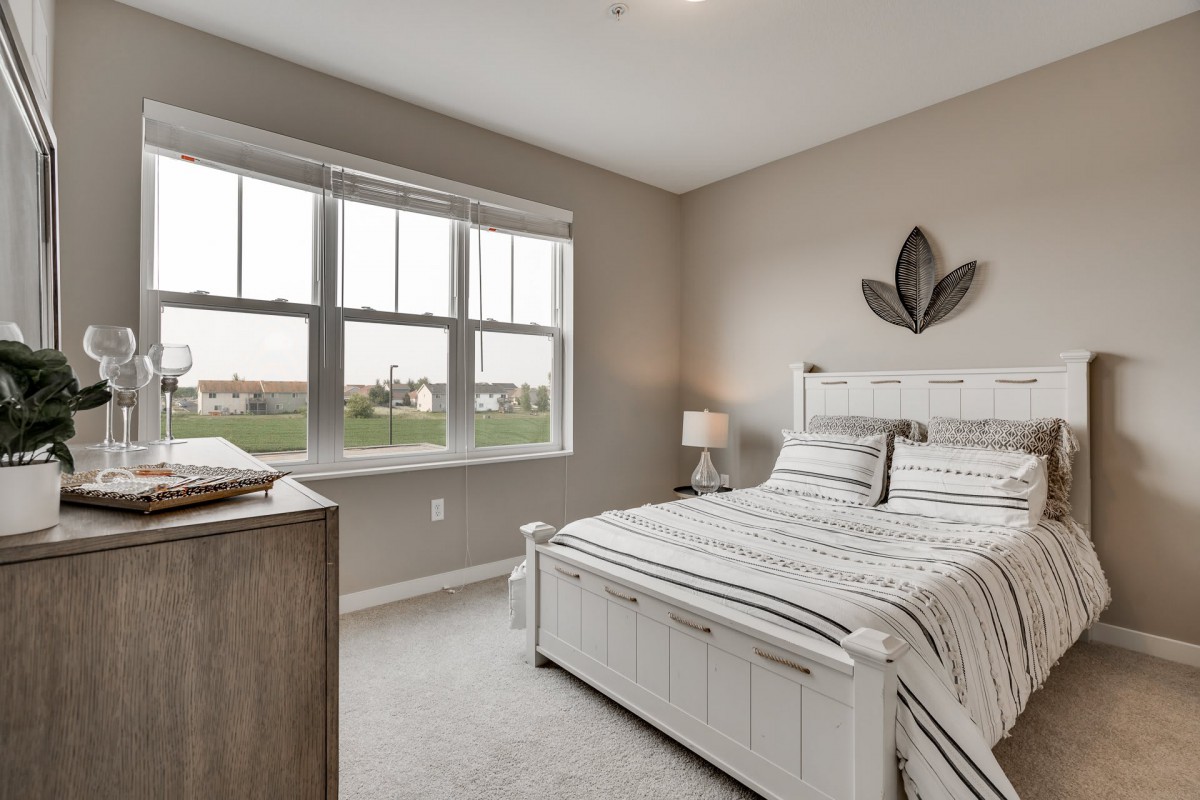 A modern and minimalist bedroom with neutral tones and ample natural light streaming through the window.