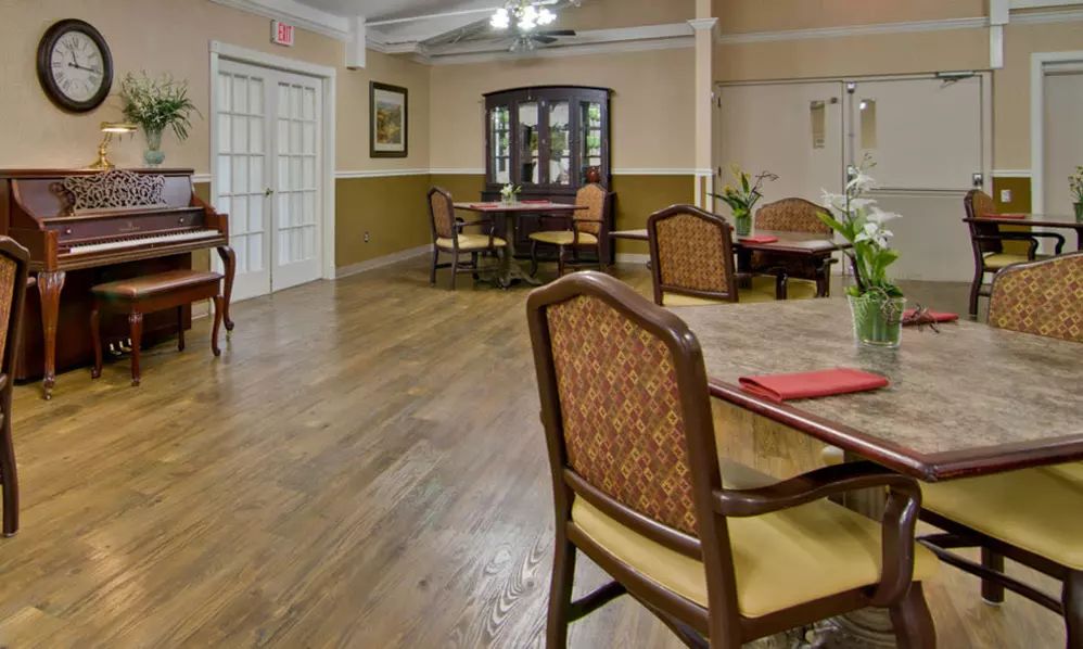 A well-furnished dining room with elegant chairs and tables on a hardwood floor.