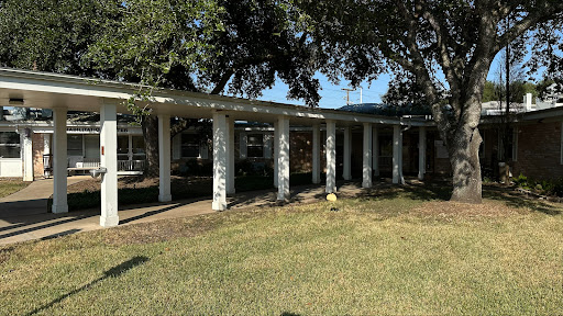 A modern architectural structure featuring columns and greenery.