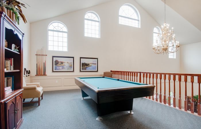 A spacious loft game room featuring a pool table, large windows, and stylish decor.