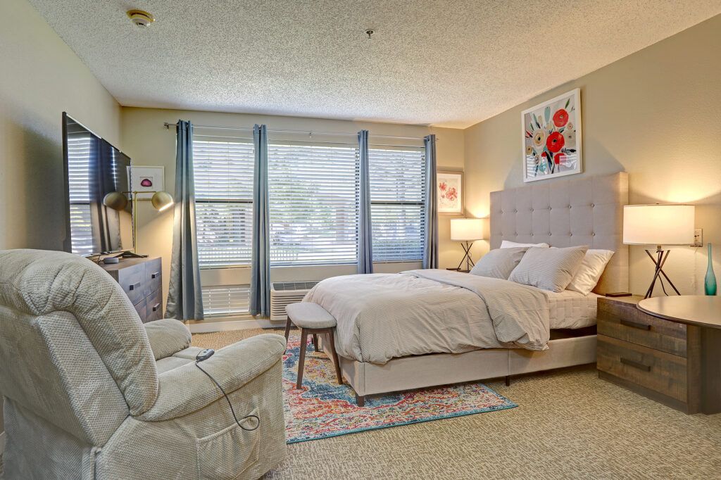 A cozy and modern bedroom with natural light streaming through large windows.