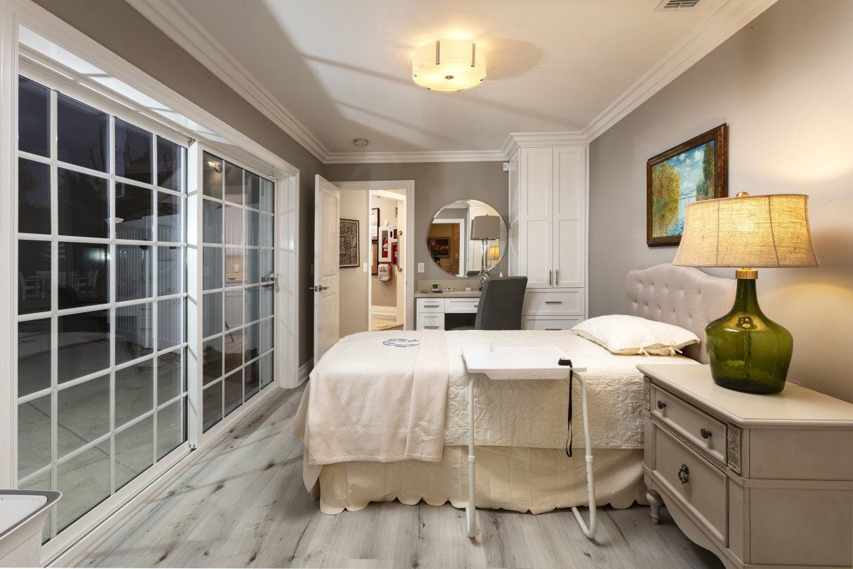 A modern and cozy bedroom featuring a neatly made bed, stylish furniture, and sliding glass doors leading to an adjacent room.
