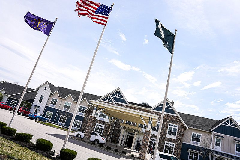 A building with multiple flags displayed at the entrance under a clear sky.
