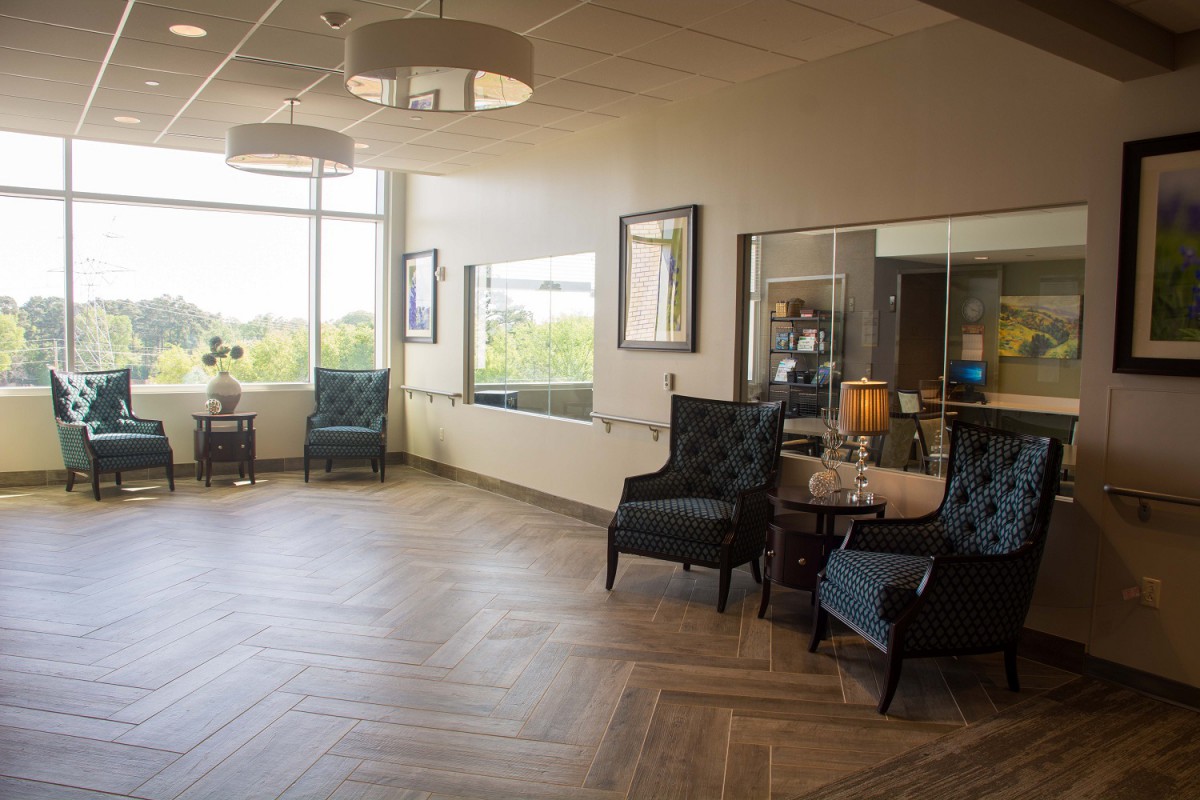 A cozy waiting room featuring stylish chairs, large windows, and elegant lighting.