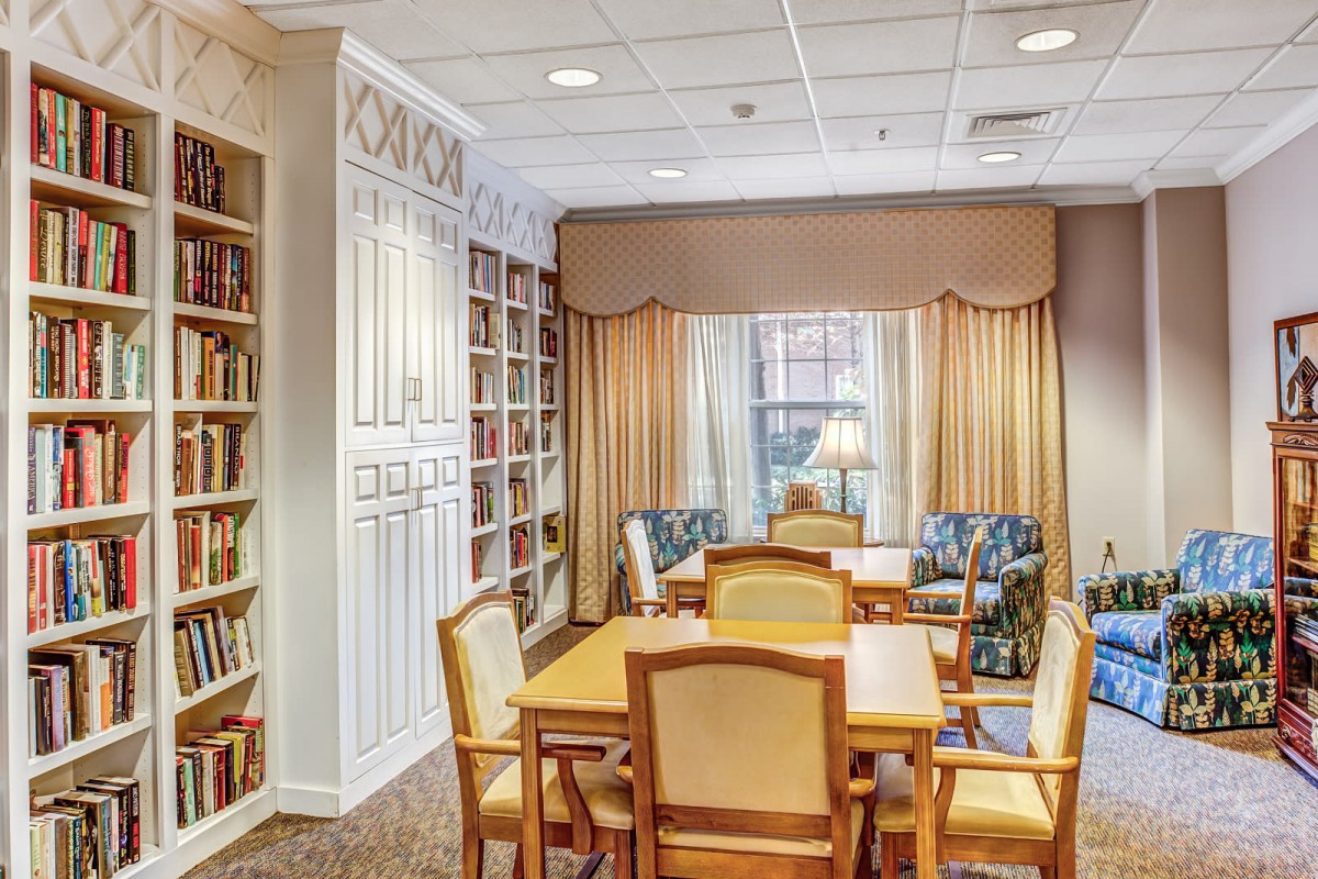 A cozy library reading room with bookshelves, a table, and chairs.