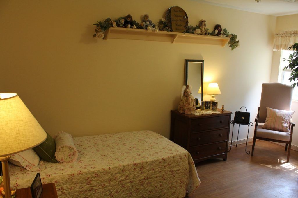 A cozy bedroom with a single bed, dresser, and decorative shelf.
