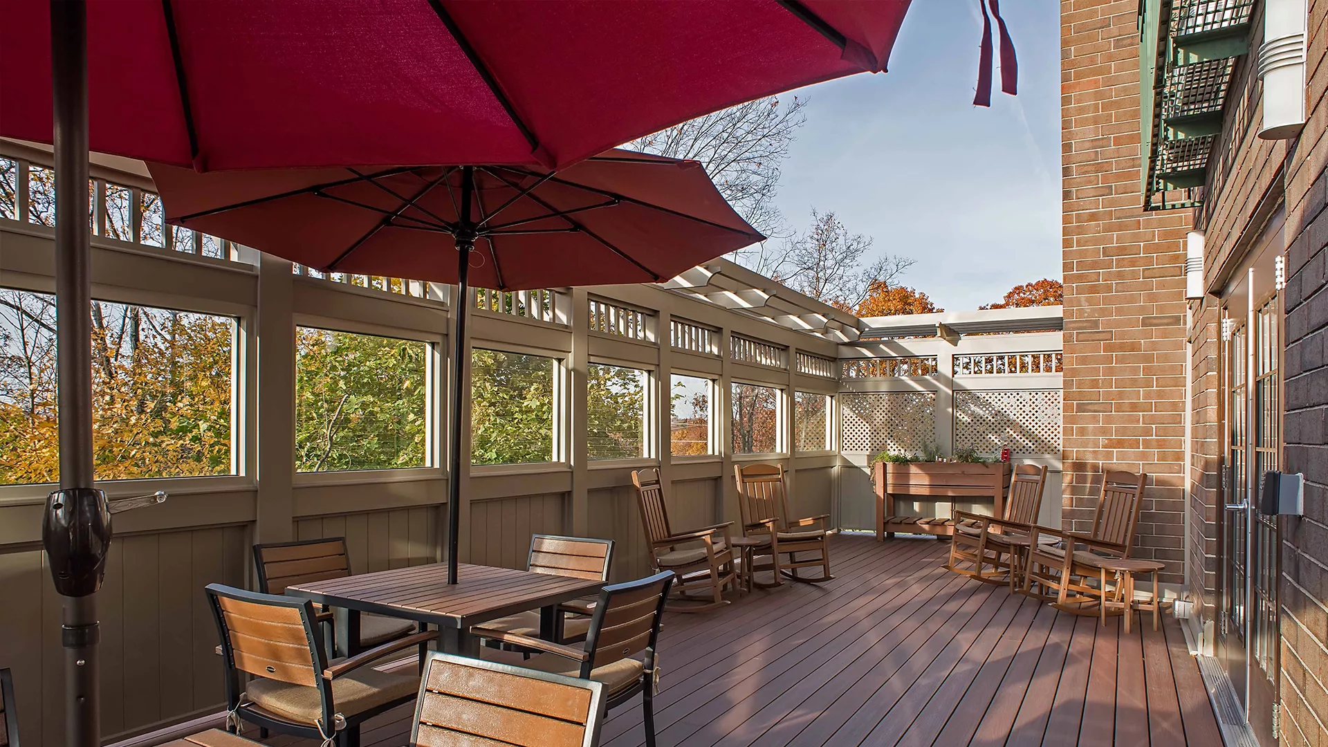 A spacious outdoor patio with wooden furniture and large red umbrellas.