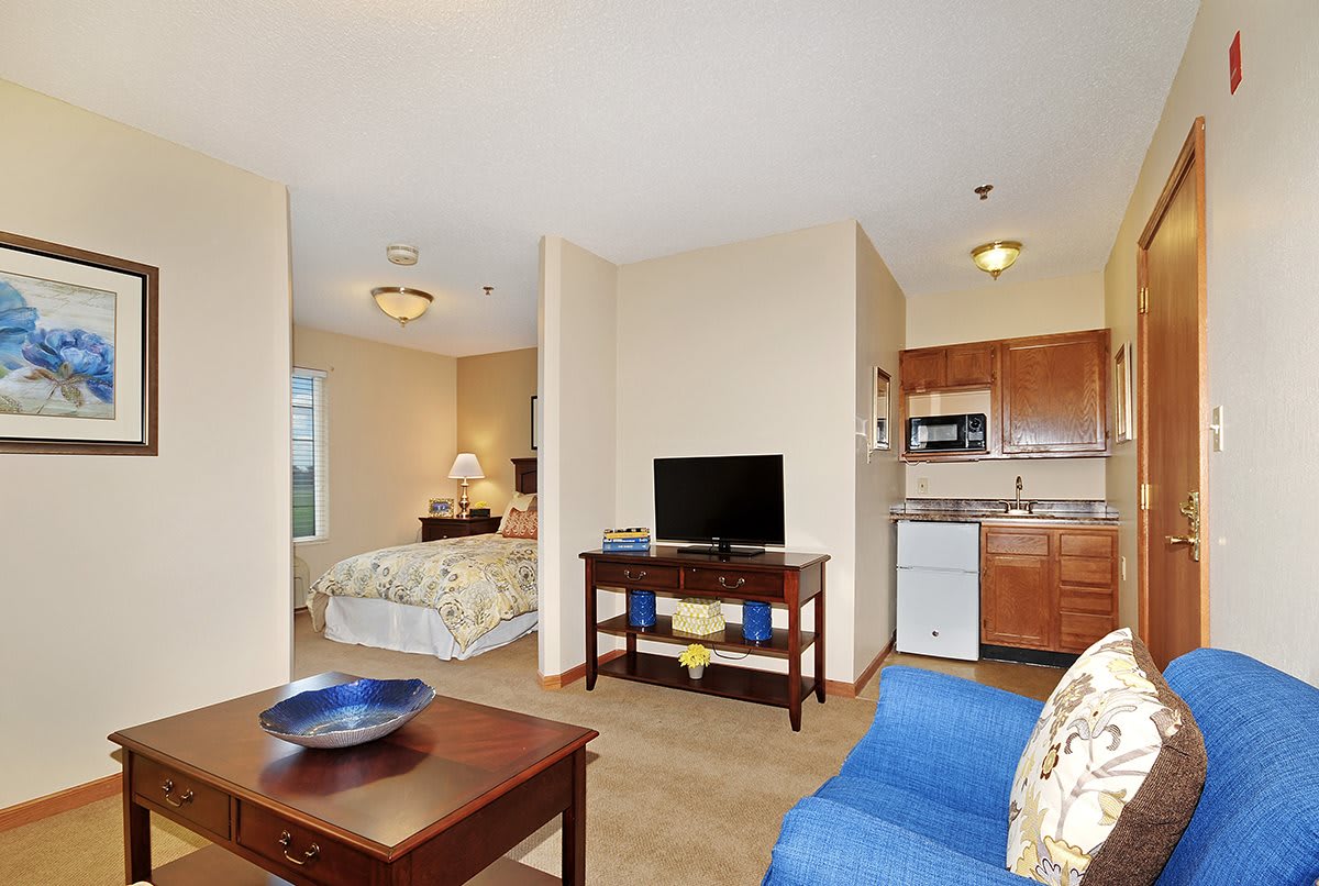 A cozy apartment interior featuring a combined living area, bedroom, and kitchen space with modern furnishings.