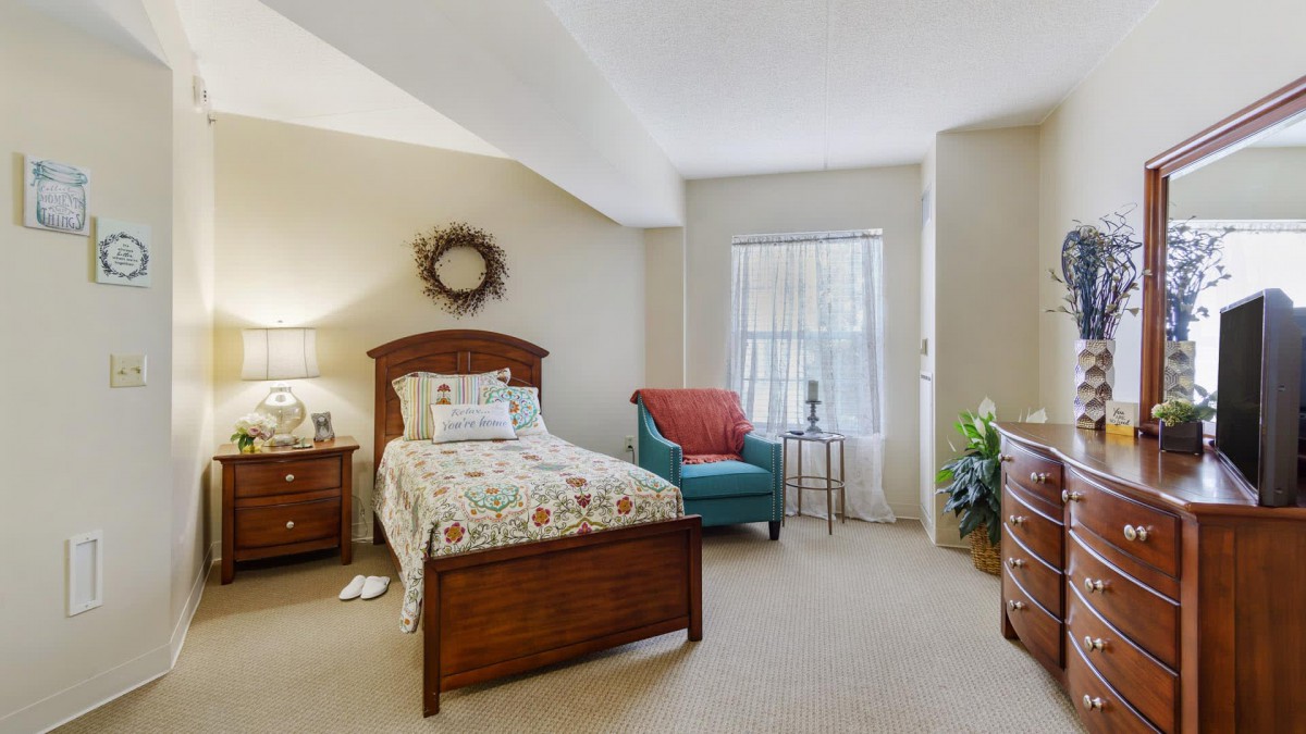 A cozy bedroom with a single bed, armchair, and window.