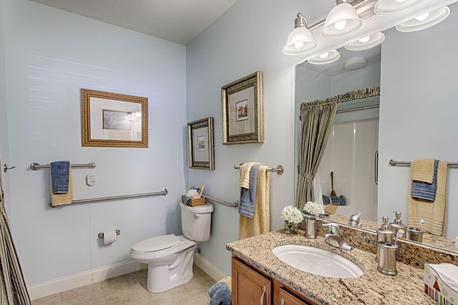 A well-decorated bathroom featuring a sink with a granite countertop, framed art on the walls, and neatly arranged towels.