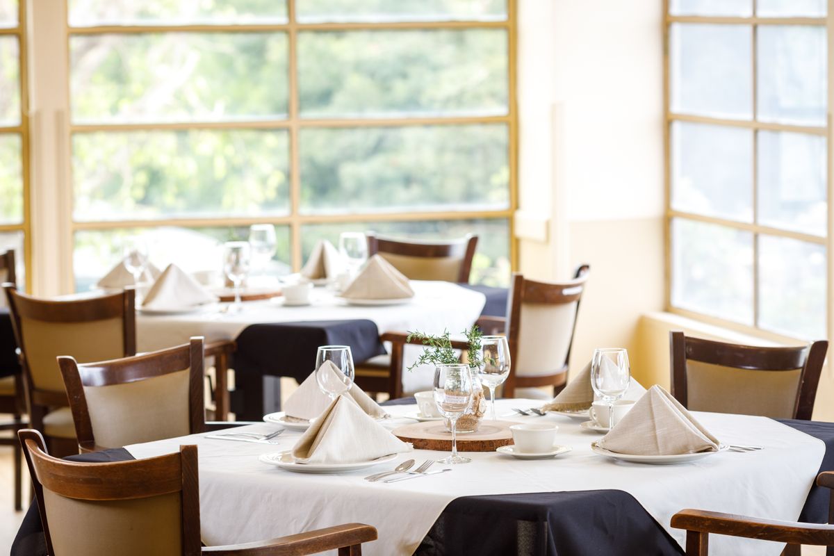A well-appointed dining room with neatly set tables and chairs, featuring elegantly folded napkins and glassware.