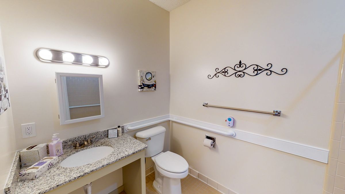 A clean and modern bathroom with a granite countertop and decorative wall elements.