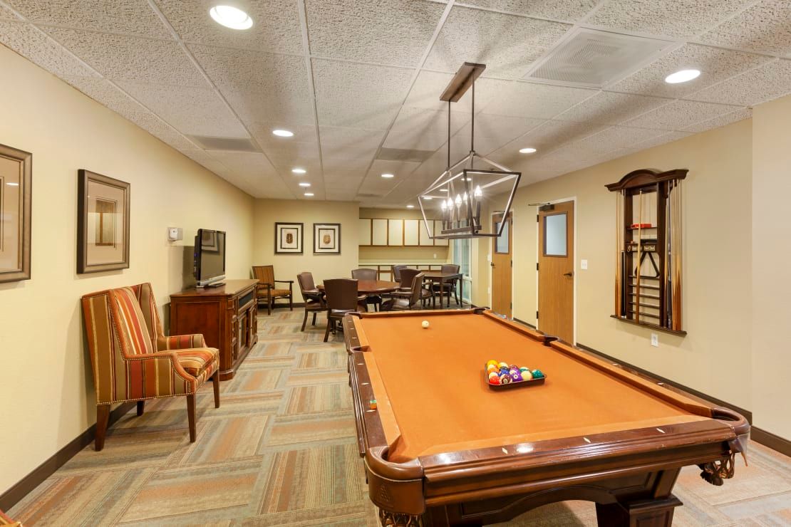 A well-furnished billiard room with a pool table and seating area.