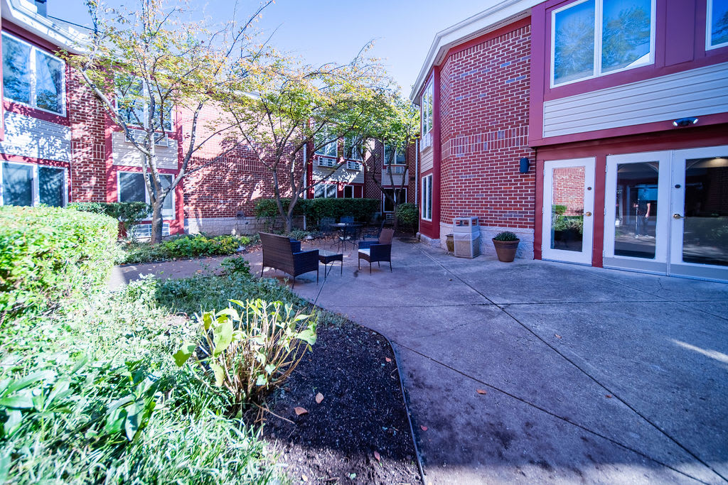 A peaceful courtyard with outdoor seating next to a red brick building on a sunny day.