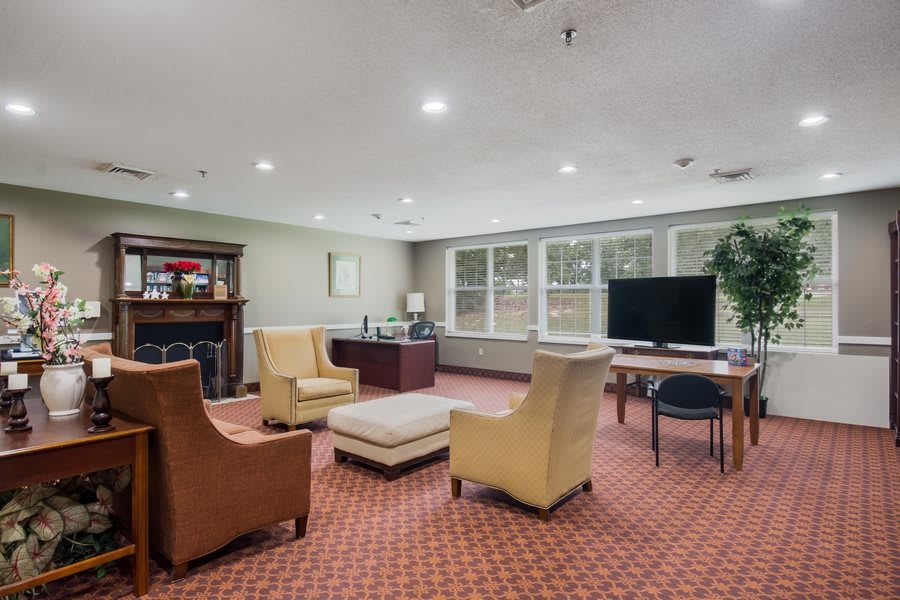 A cozy and well-furnished living room or office space with a seating area, television, and desk.