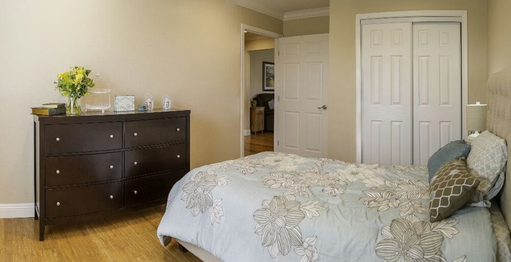 A cozy bedroom with floral bedding and a dark wooden dresser.