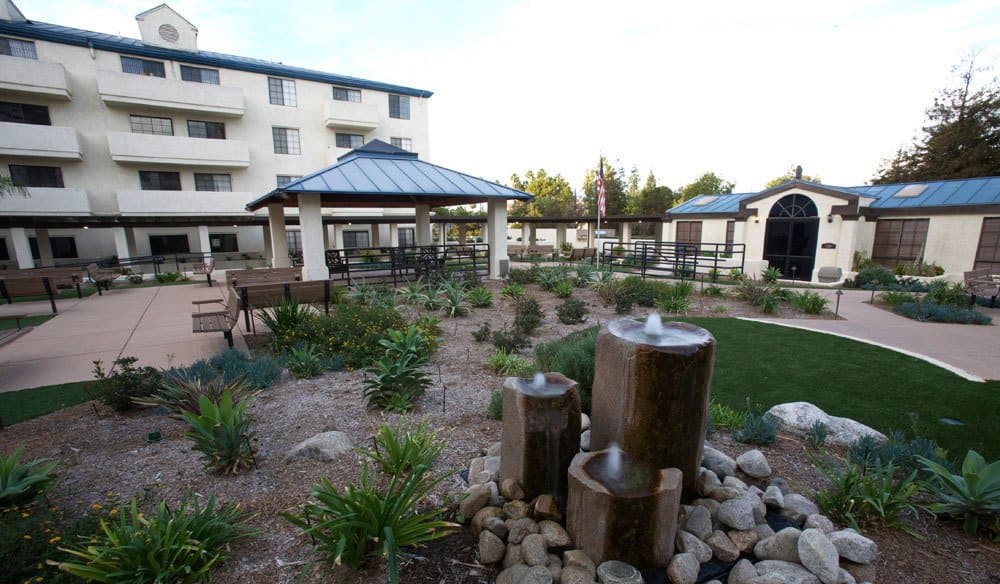 A well-maintained garden with a fountain and gazebo in an apartment complex courtyard.