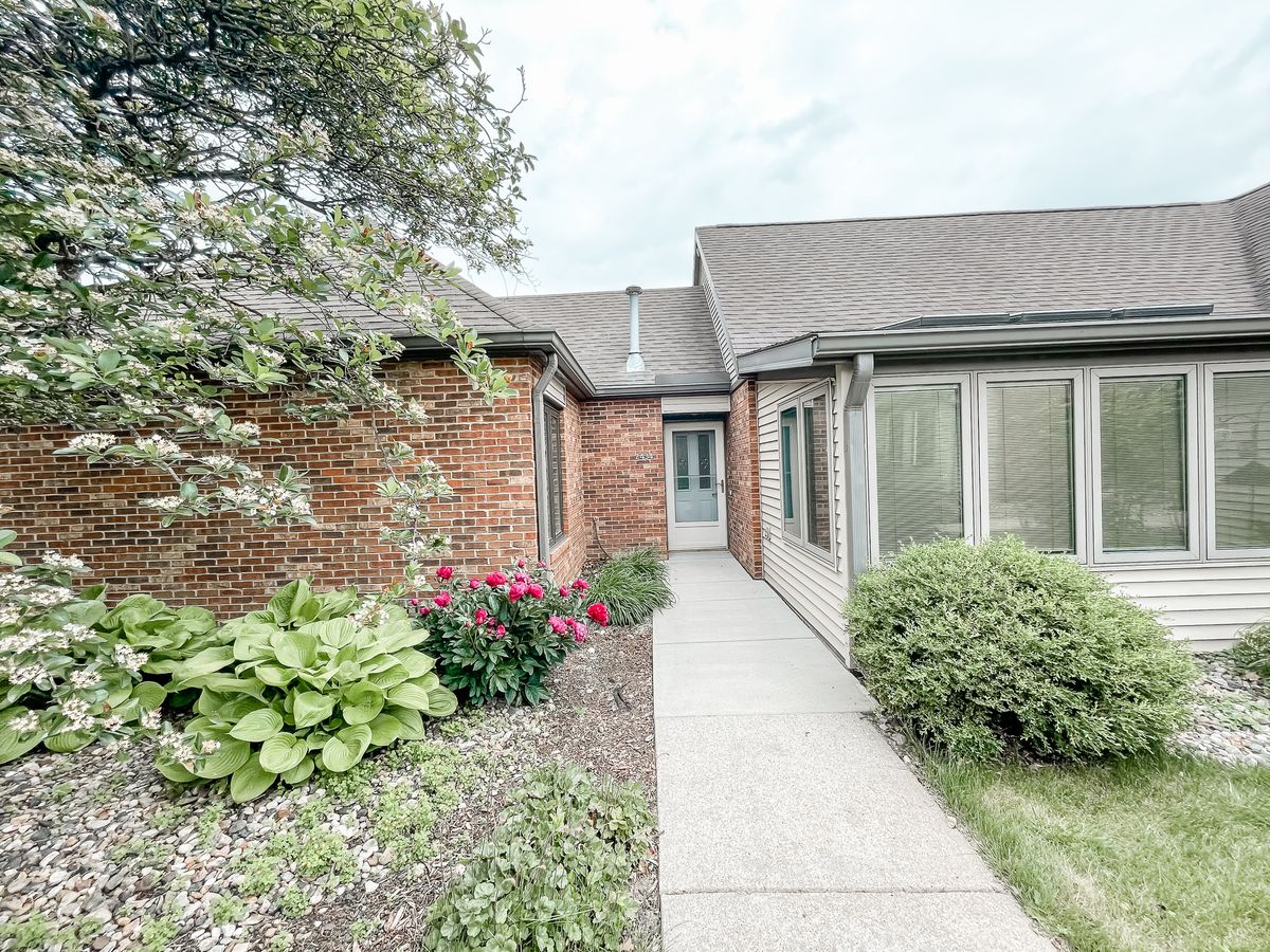 A cozy brick house with a paved pathway surrounded by a well-maintained garden.