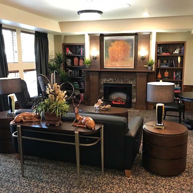 A cozy living room with a fireplace, surrounded by bookshelves and comfortable seating.