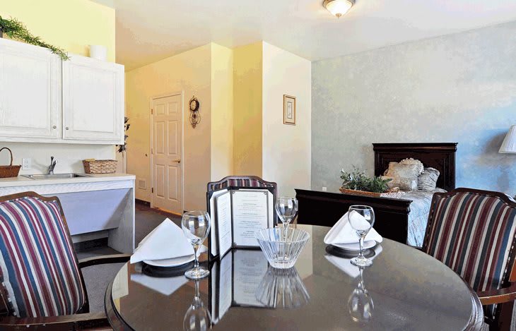 A cozy home interior with a set dining table and a view of the kitchen and bedroom.