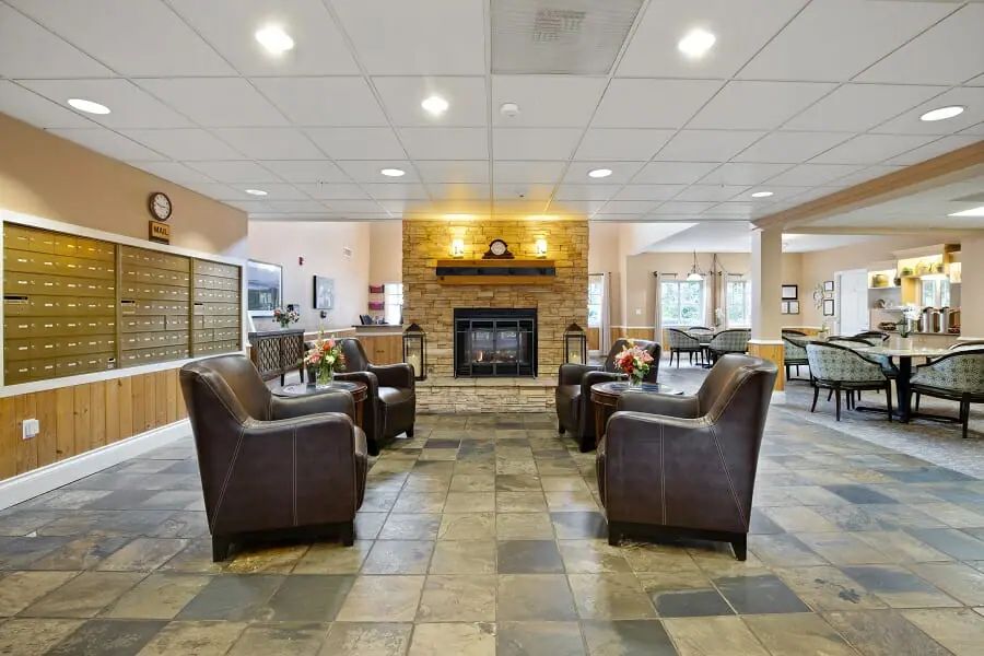 A modern lobby with leather chairs and a central fireplace.