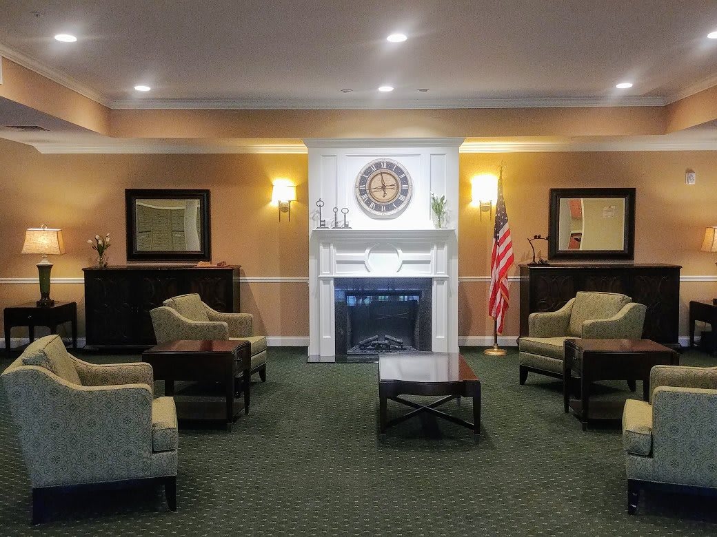 A warmly lit lobby with a comfortable seating area, featuring a fireplace and an American flag.