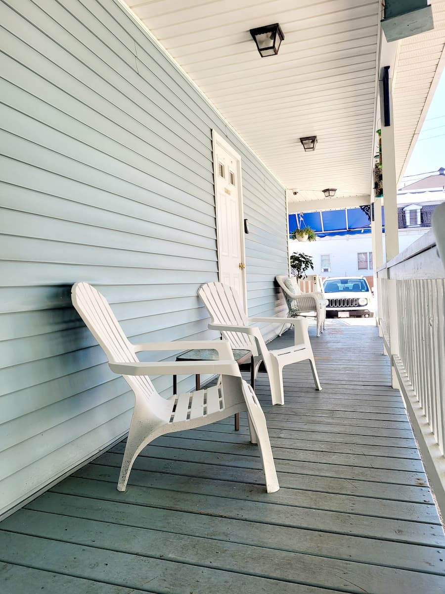 A cozy porch with white chairs offers a perfect spot for relaxation.