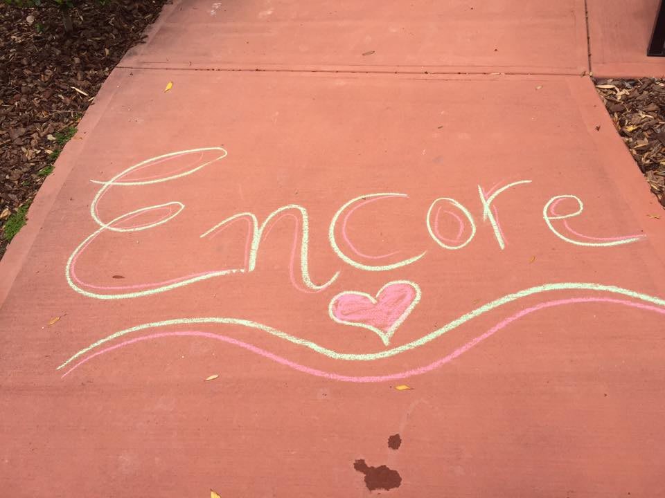 Chalk drawing on a sidewalk featuring the word 'Encore' with a heart.