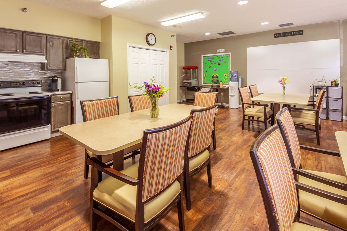 A cozy dining area with tables, chairs, and a kitchen space.