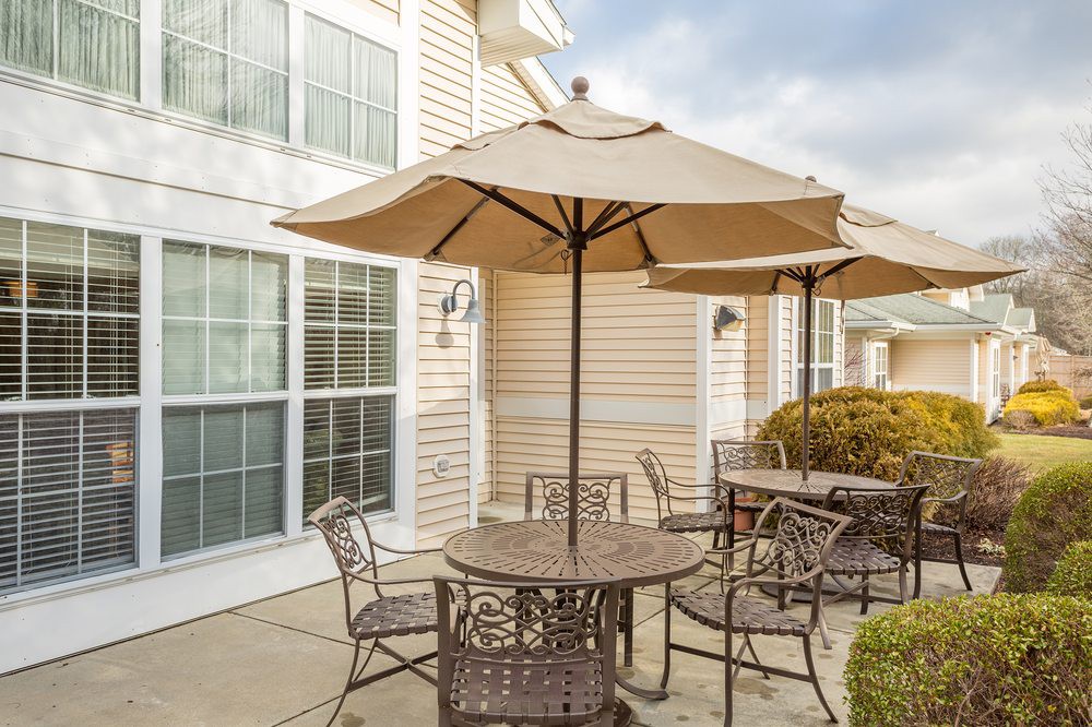 A cozy outdoor patio area with a table and chairs under a large umbrella.