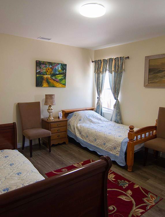A cozy bedroom with two single beds, chairs, and decorative wall art.