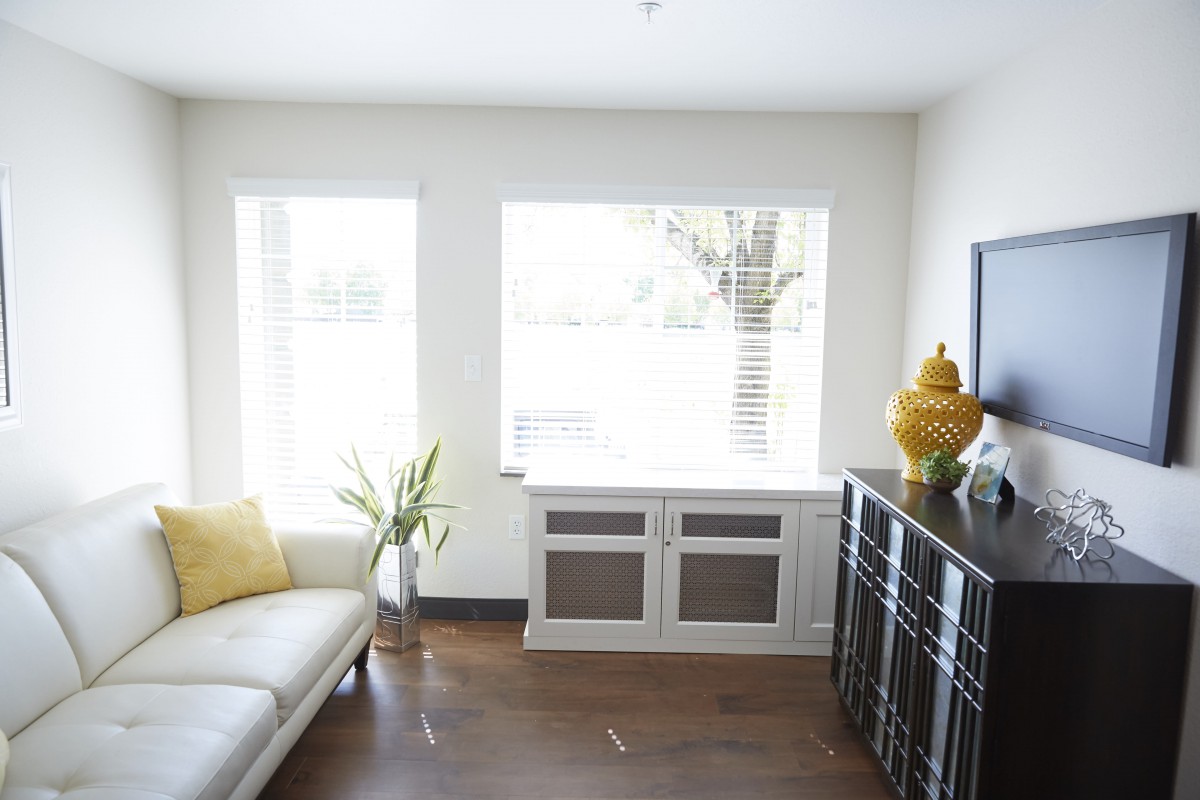 A modern and minimalist living room with a white sofa, decorative elements, and large windows.